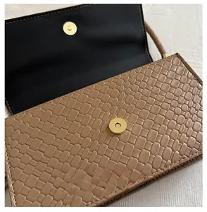 Detail of woven texture shoulder bag with gold magnetic snap closure and black lining