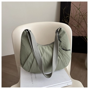 Détail du sac dumpling en nylon plissé vert pâle avec bandoulière grise réglable