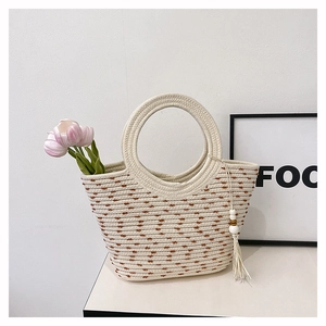 Détail du sac seau en paille avec poignée circulaire et breloque à pampilles perlées