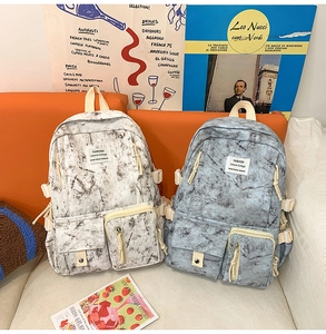 Detailed view of marble print backpacks with buckle straps on a modern orange sofa