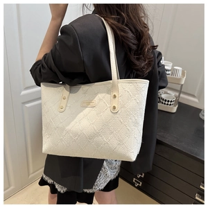 Detail shot of white woven tote bag showing the texture and brand logo on minimalist style