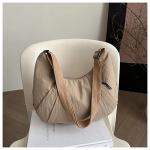 Détail du sac croissant en nylon plissé kaki avec bandoulière large en toile et cordon de serrage