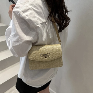 Détail d'un sac bandoulière en paille tissée avec noeud métallique élégant et bandoulière cuir