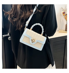 Detail of straw woven bag with sky blue leather trim and golden flower clasp