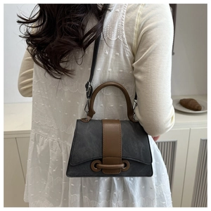 Close-up of contrast crossbody bag with gray canvas texture and brown leather strap detail