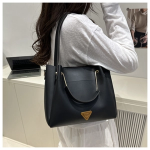 Detail of black leather tote bag with gold metal hardware and luxury logo on model