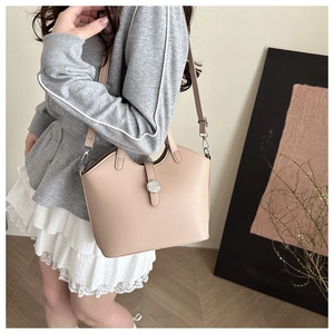 Detailed view of beige faux leather tote bag with metal logo and adjustable strap