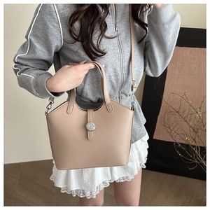 Detail view of khaki bucket bag with metallic circular logo and adjustable shoulder strap