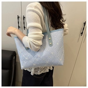Detail of light blue tote bag featuring embossed floral diamond patterns and gold studs