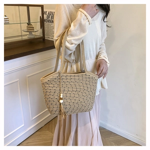 Detail of hand-woven straw tote bag with elegant tassel charm and striped pattern