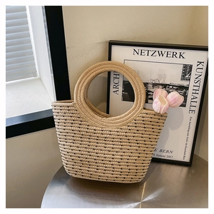 Détail du sac cabas en paille tissée avec anses rondes et rayures noires chic sur table