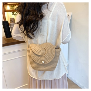 Detailed view of handmade woven straw bag with spiral lid and pearl closure