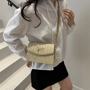 Détail du sac bandoulière tissé beige avec boucle élégante en nœud métallique sur le rabat