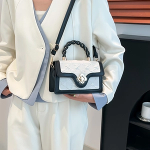 Close-up of contrast crossbody bag with woven handle and elegant floral metal twist lock