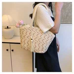 Detail of woven straw tote bag with brown polka dots and elegant tassel wood bead charm