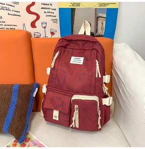 Macro view of burgundy marble backpack with dual front pockets on orange sofa