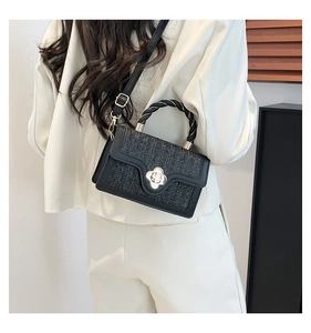Detail of black woven shoulder bag with golden clover-shaped lock and rope handle