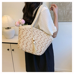Detail of woven straw tote bag with polka dots and beaded tassel in home setting