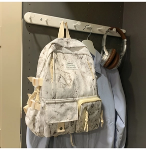 Detail of white marble print canvas backpack with dual front pockets and top handle strap