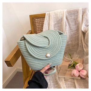 Détail d'un sac seau tissé main vert menthe avec fermoir perle et texture en spirale unique