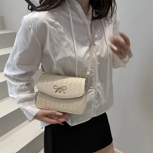Détail du sac bandoulière tissé crème avec fermoir décoratif en nœud doré
