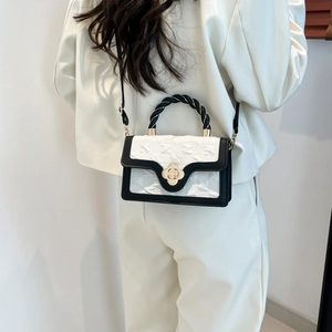 Detail of crossbody bag with black braided handle and golden camellia floral buckle