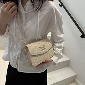 Gros plan détaillé du sac bandoulière tissé beige avec boucle nœud en métal doré