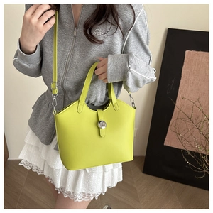 Detailed shot of fluorescent yellow trapezoid handbag with silver buckle and thin strap