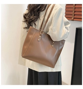 Detailed view of brown tote bag with gold ring hardware and sleek decorative stitching