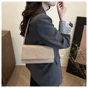 Detail of beige woven texture baguette bag with metallic hardware and sleek strap