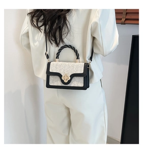 Detail of a straw texture crossbody bag with floral metal clasp and braided handle
