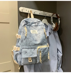 Close-up of blue marble tie-dye backpack with double front pockets and woven zipper pulls