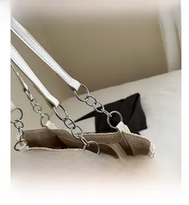 Detail of straw woven bag showing silver chain links and white leather handle attachment