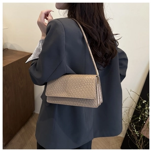 Detailed close-up of beige woven texture and slim shoulder strap on fashion square bag