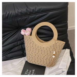 Détail d'un sac seau en paille tissé à la main avec pois noirs et pompons en perles