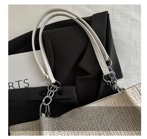 Detail of woven tote bag showing white leather handle and silver metal chain strap