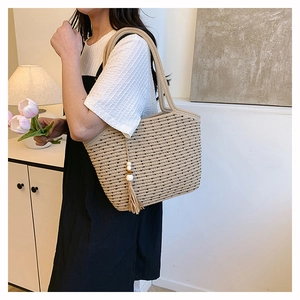 Close-up of beige straw tote bag featuring black polka dots and soft tassel charm detail