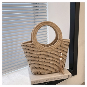 Texture détaillée du sac seau en paille beige à pois noirs avec une grande poignée ronde