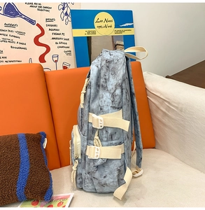 Detail of blue marble pattern backpack with adjustable beige straps on an orange sofa