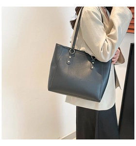 Detail of black tote bag with premium faux leather texture and gold metal ring hardware