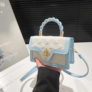 Detail of light blue crossbody bag with braided handle and golden flower twist lock