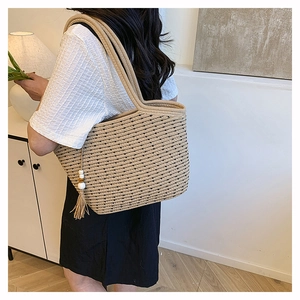 Detail view of woven straw tote bag featuring black polka dots and wooden bead tassel