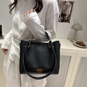 Elegant black minimalist tote bag with golden hardware shown in a lifestyle interior