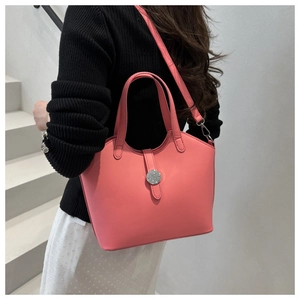 Pink matte tote bag crossbody style shown with round silver buckle detail on model