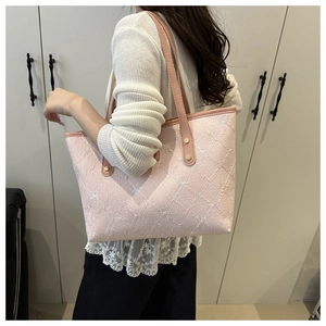 Pink tote bag with white bow embroidery shown on shoulder for size and style reference