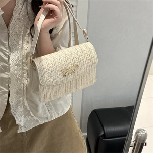 Détail du sac en paille tressée crème avec fermoir nœud doré et texture à chevrons