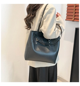 Close-up of a large black tote bag with long shoulder straps and gold metal buckles