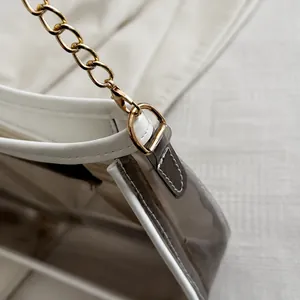 Detail von weißem Lederbesatz und transparentem PVC-Material mit goldener Kette