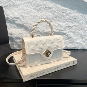 Detail of rose embossed cream handbag with clover twist lock and braided handle