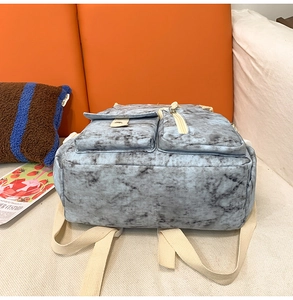Detail of blue-grey marble texture canvas backpack with beige straps and front pockets